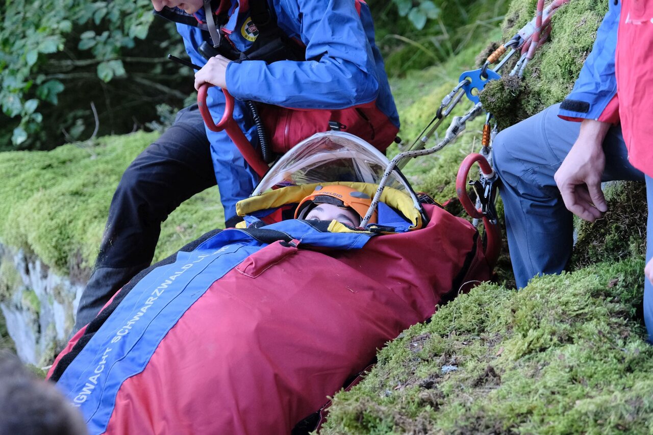 Die verletzte Person liegt eingepackt in einer Schlafsack-ähnlichen Decke