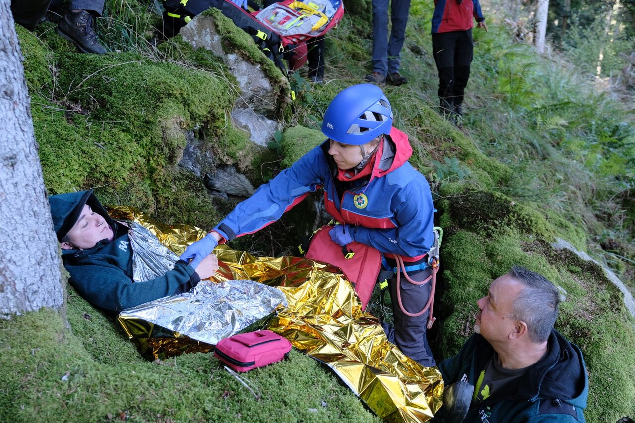 Liegende Person wird von der Bergwacht mit einer Rettungsdecke bedeckt