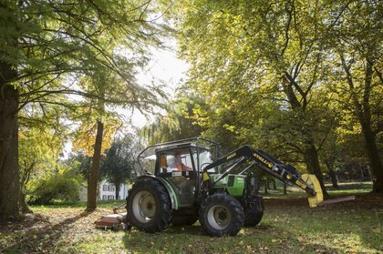 Auf abgegrasten Wiesen zwischen Bäumen wird mit dem traktorgezogenen Mulcher nachgepflegt
